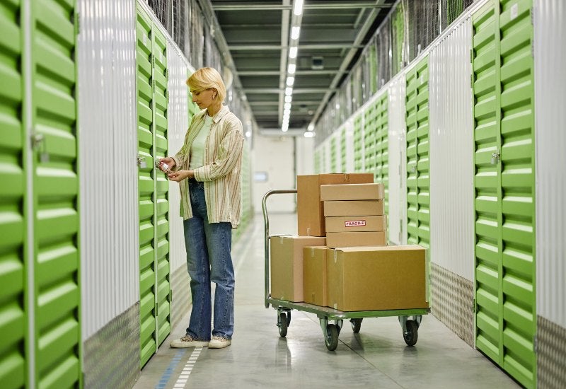 A woman at a storage unit with boxes, promoting ways to save on storage unit costs in Mountain View